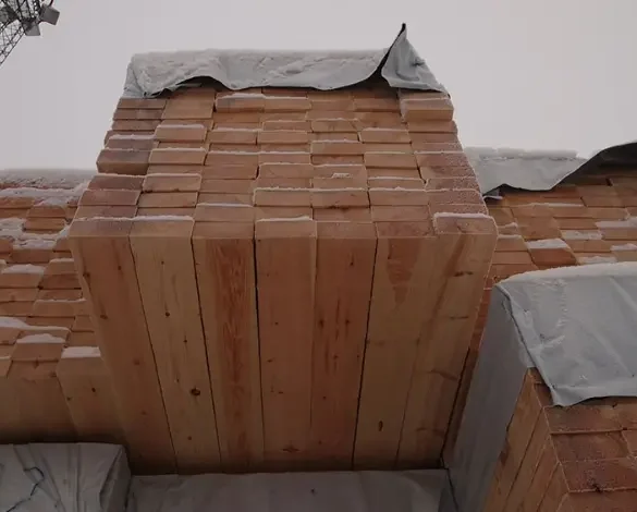 Piles de bois scié en Suède recouvertes de bâches, représentant la hausse des prix du bois en 2024