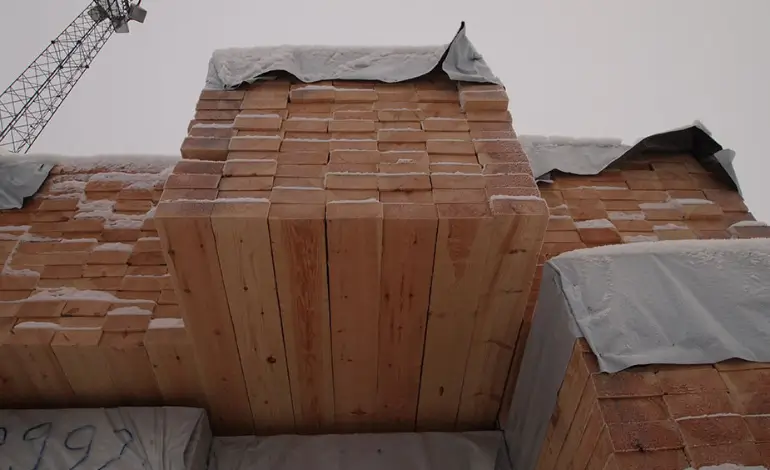 Piles de bois scié en Suède recouvertes de bâches, représentant la hausse des prix du bois en 2024