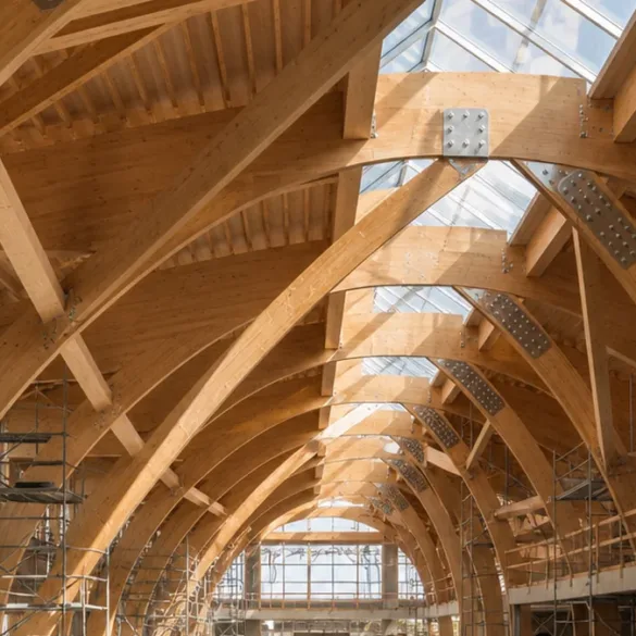 imposantes poutres cintrées en bois lamellé-collé clair formant la nef d'un édifice dans le secteur Construction & Architecture Bois au Maroc & International